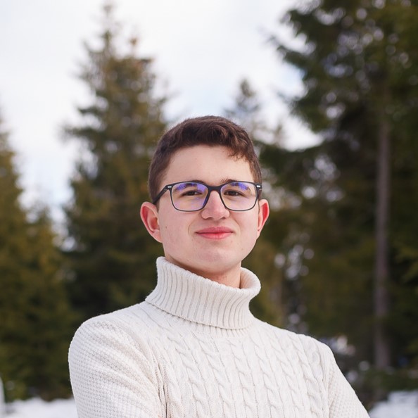Andrei in the woods, wearing a beige sweater